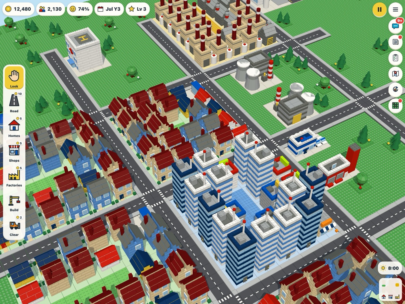 A Brick City town on an iPad: rows of brick houses with red roofs, a cluster of blue and white tower blocks, factories with chimneys, a power station and a hospital, all on a green baseplate.